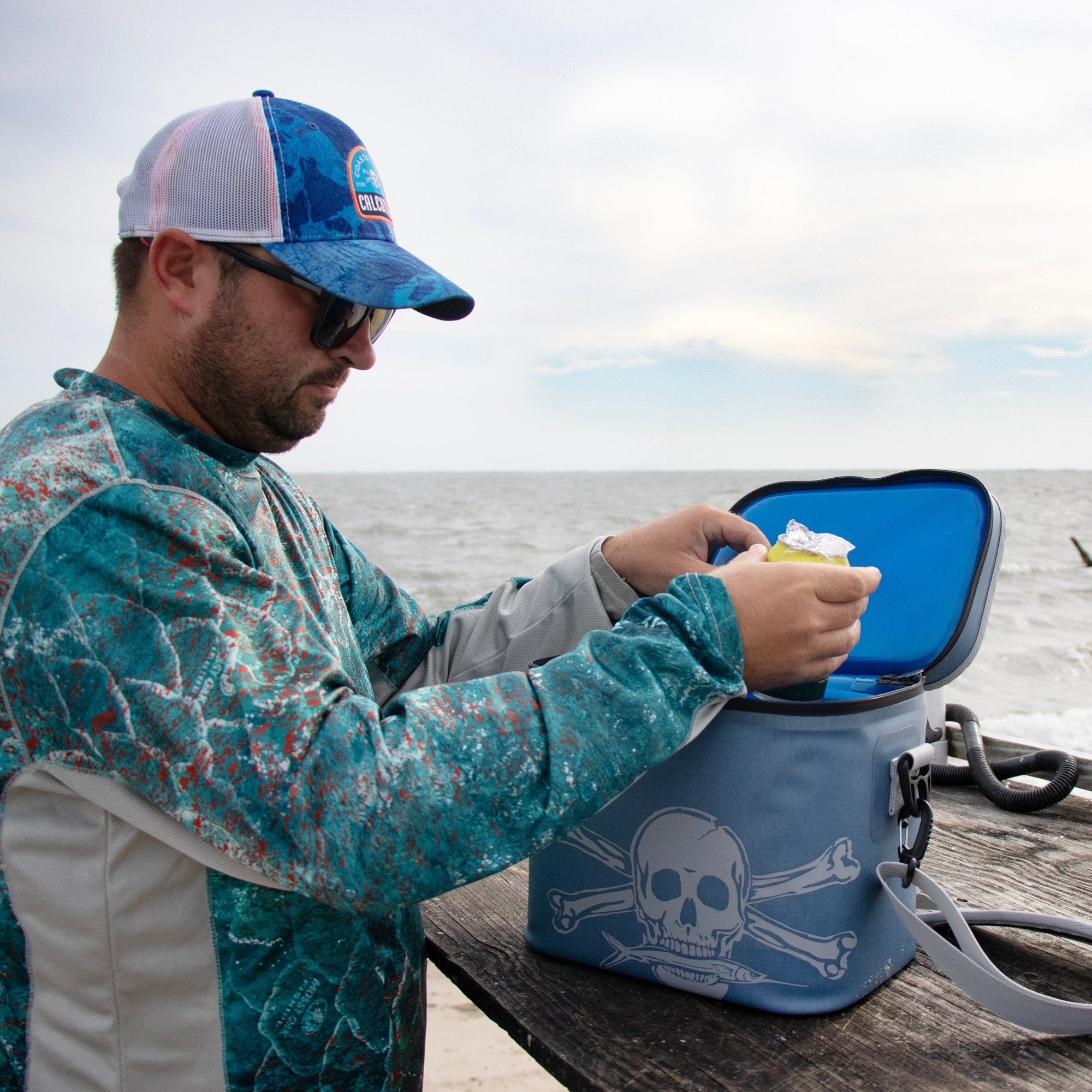 Man getting beverage from Calcutta Renegade soft cooler